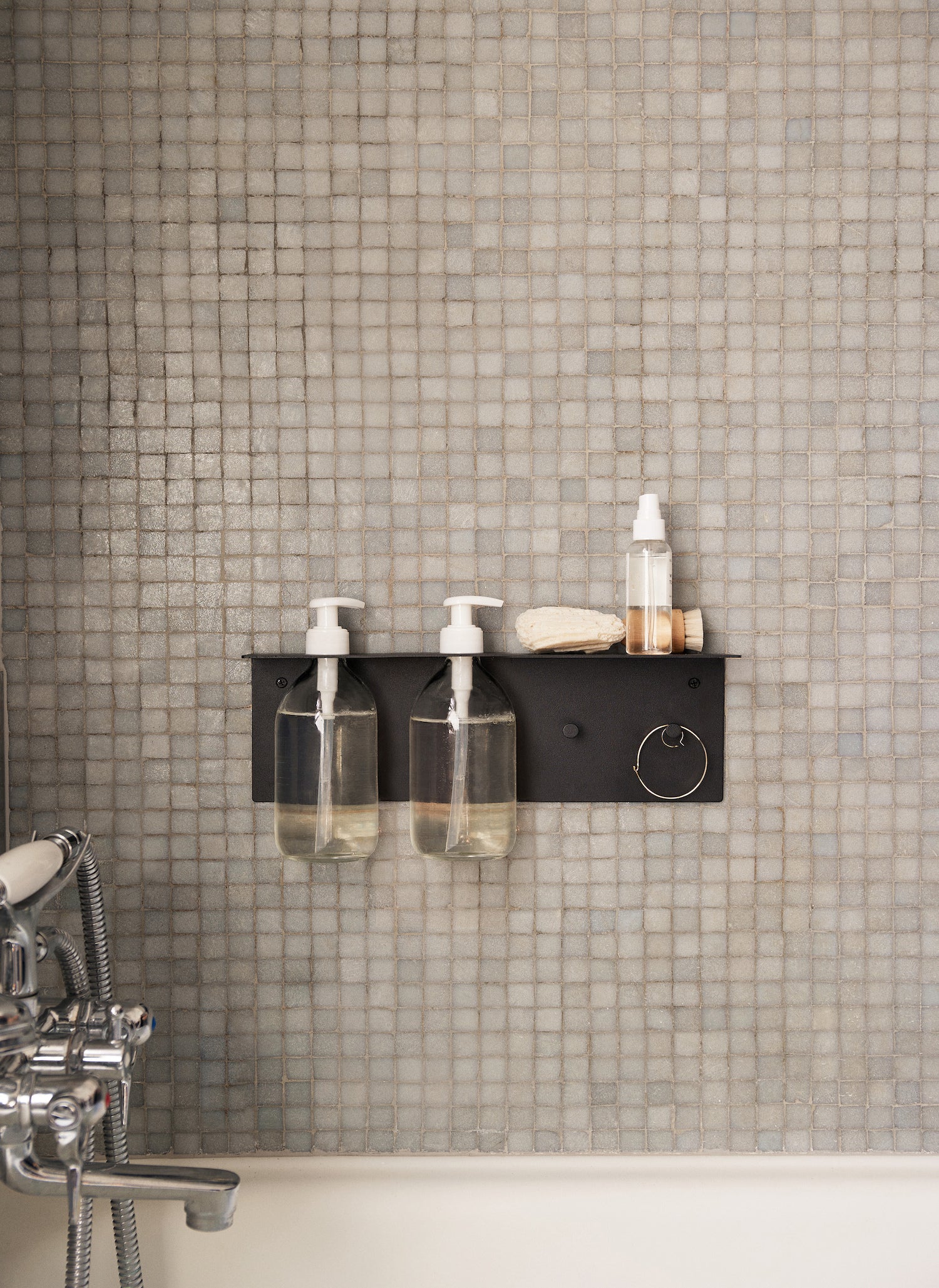 Dora Bathroom Shelf. A simple yet functional shelf featuring two holes for pump bottles, allowing you to smartly suspend them from the wall, as well as two hooks from which you can hang brushes or shower sponges. 