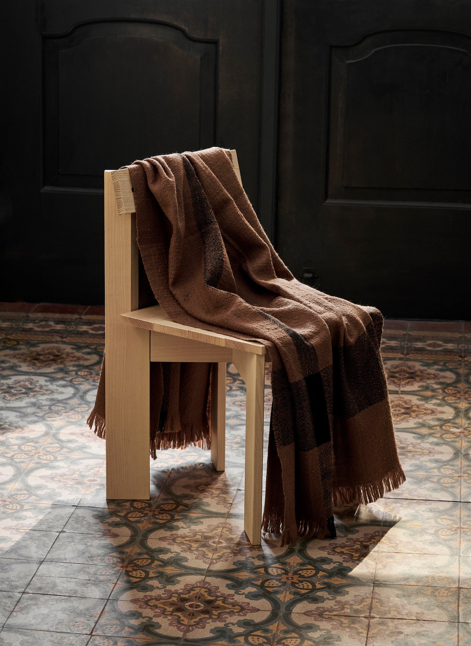 Comforting throw blanket in brown with fringe over chair.