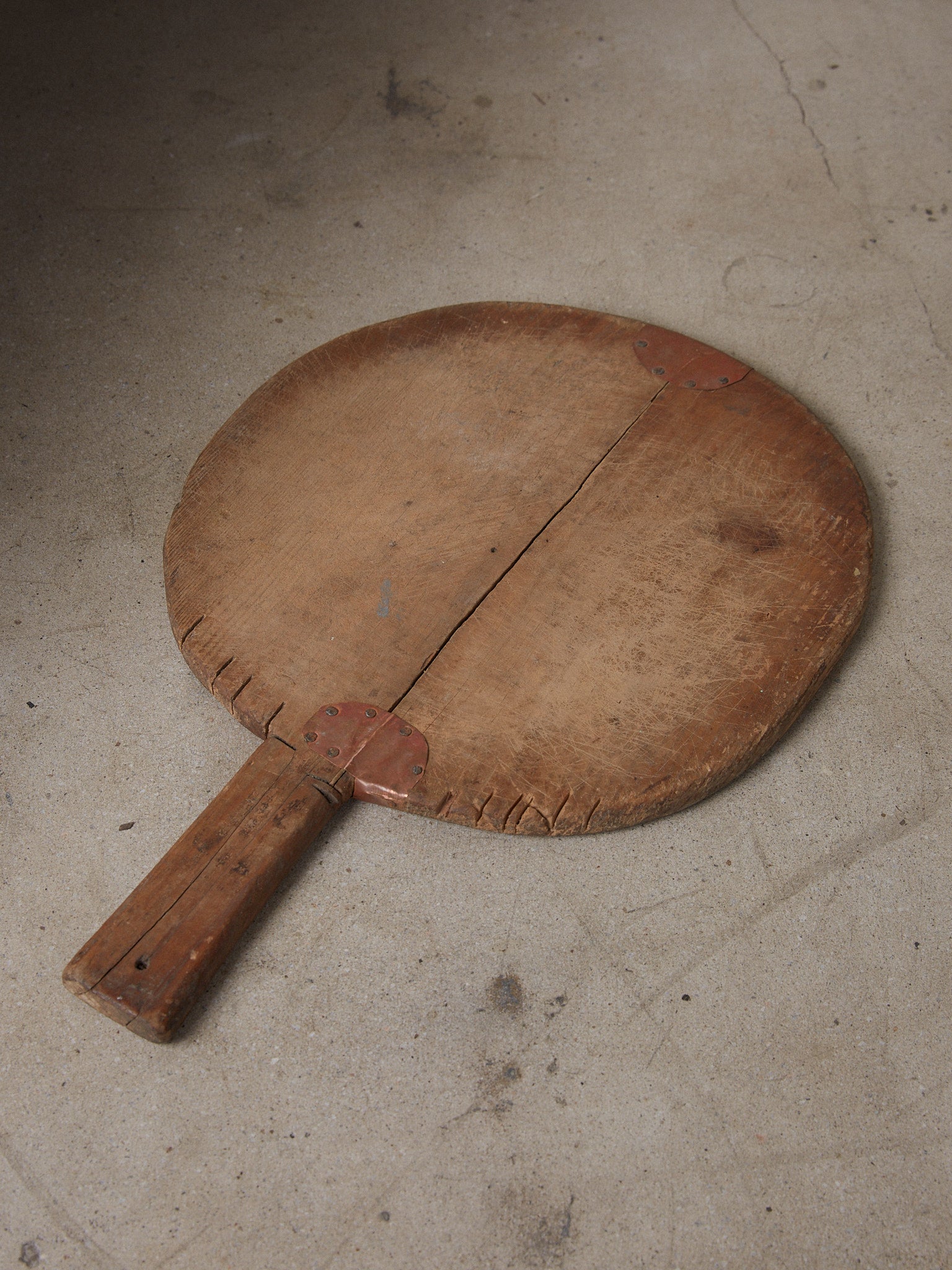 Aix Cutting Board with Repair. Rare find. Small, round handled vintage bread board in aged wood with beautiful copper repair and grain details showing the marks of history and use. 