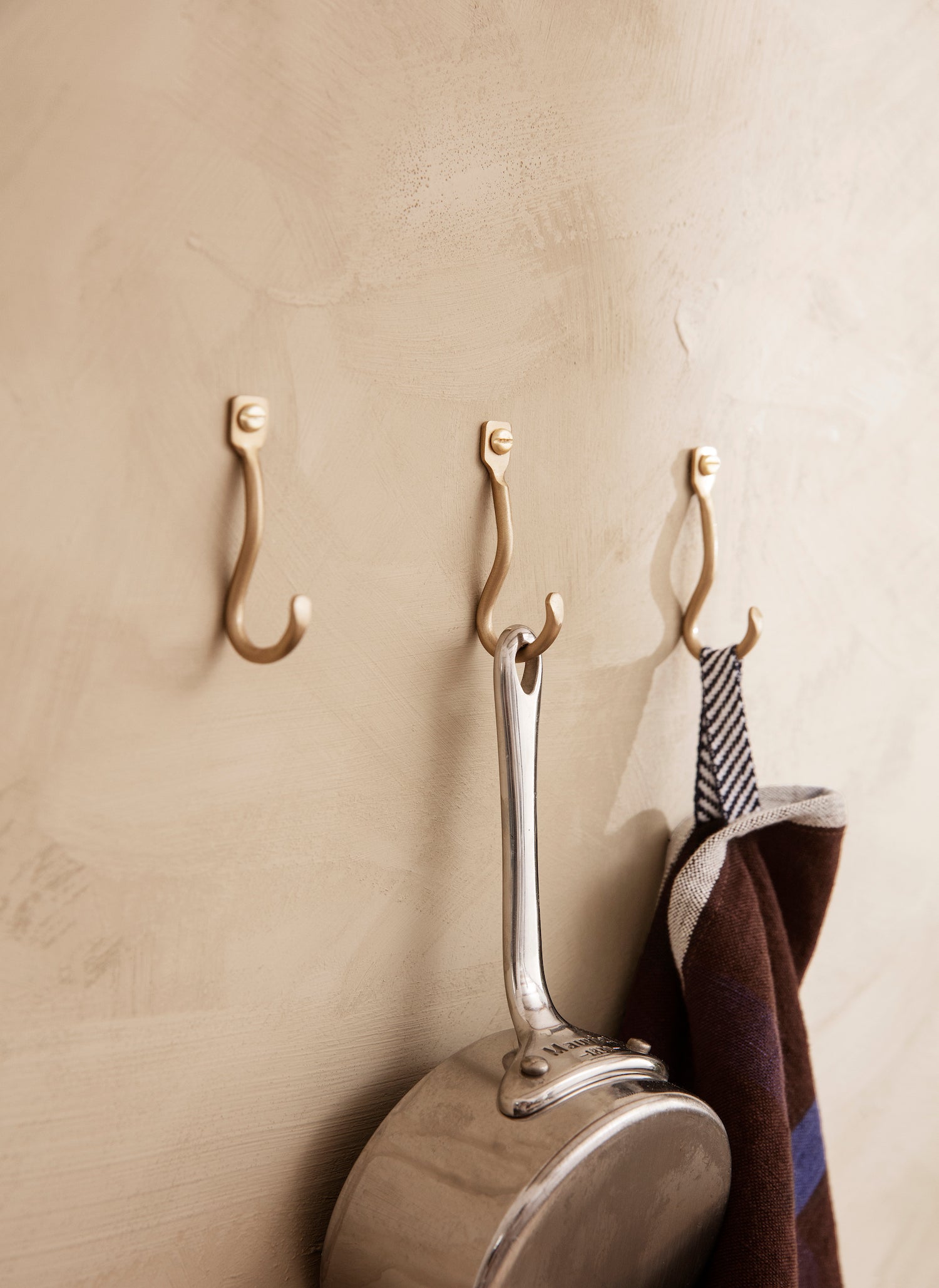 Curvature Hooks Set/3. A set of three organically shaped wall mounted hooks hand formed in pure, solid brass with a matte finish. 