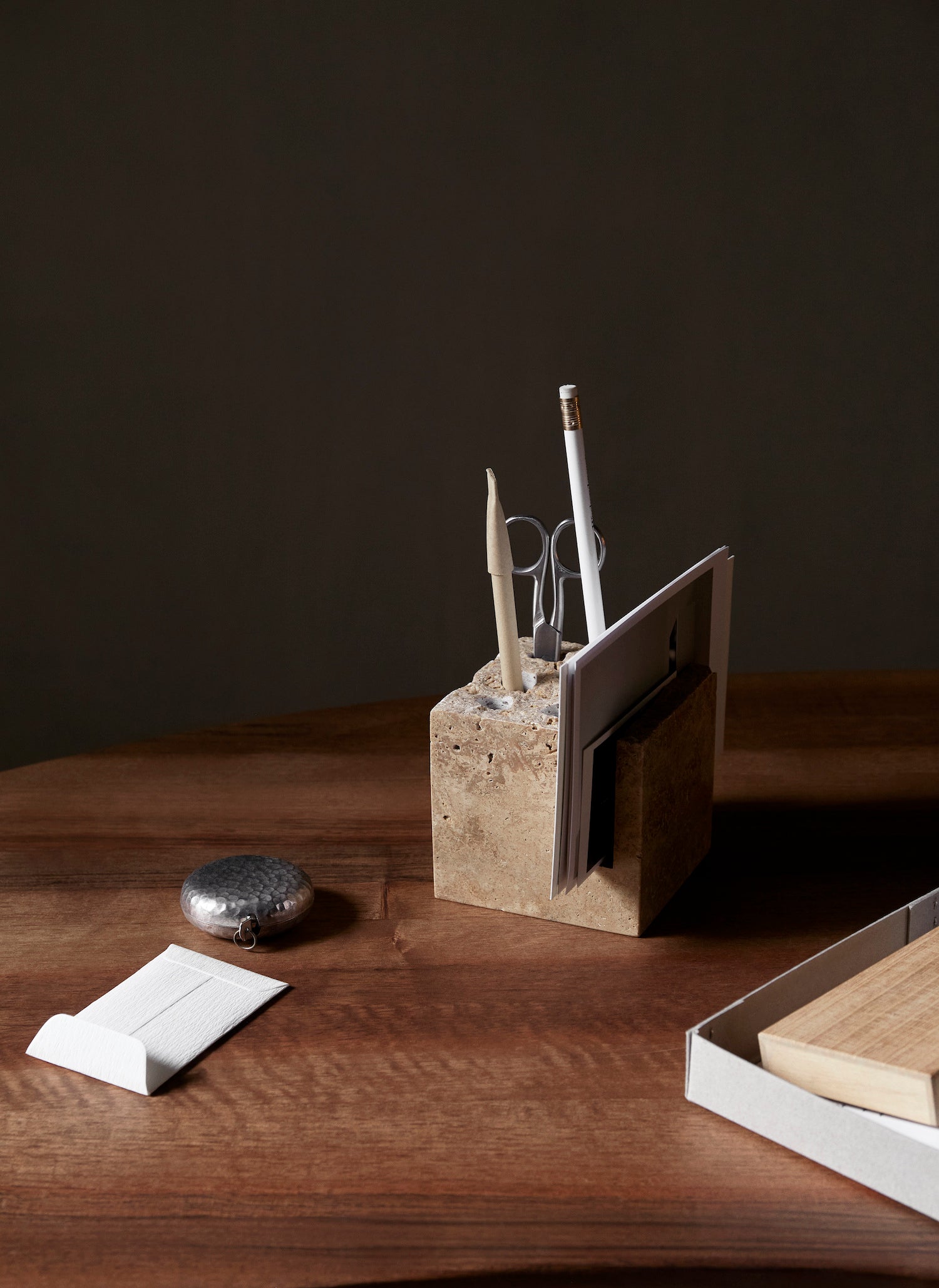 Klint Pencil Holder. An elevated, sculptural pencil holder made entirely from travertine stone with a rough, unpolished surface.