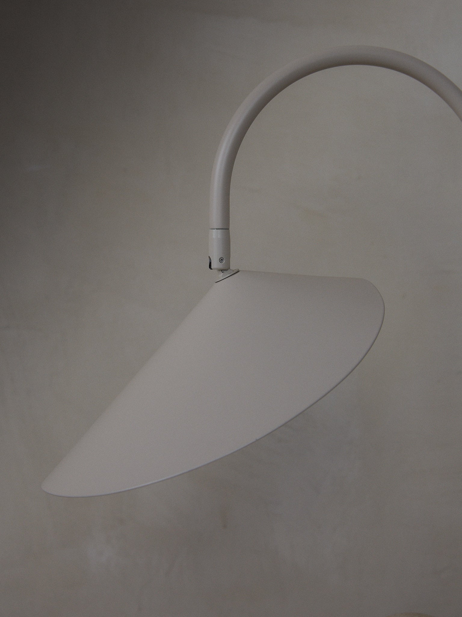 Arum Table Lamp. Statuesque, organically shaped table lamp with a beige travertine base and petal-like shade suspended from a curved metal arch. 