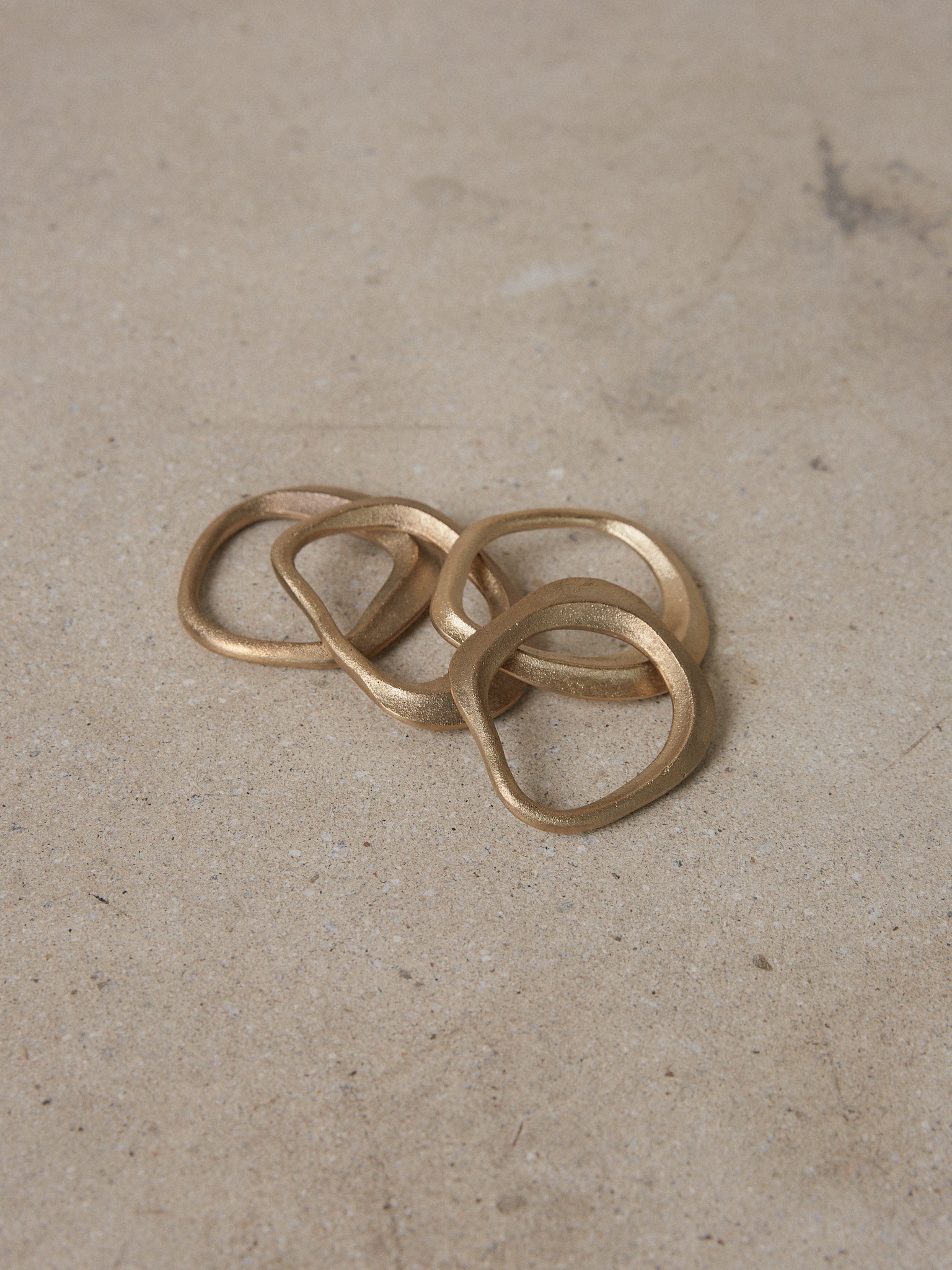 Flow Napkin Ring Set. Set of four solid cast brass napkin rings inspired by nature in flowing, organic shapes. 