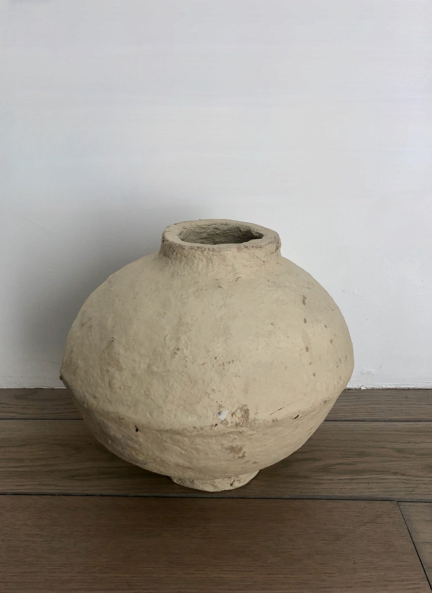 Hand crafted paper maché vessel with a wide, round bodice and distinctive tapered rim in a natural cream color.
