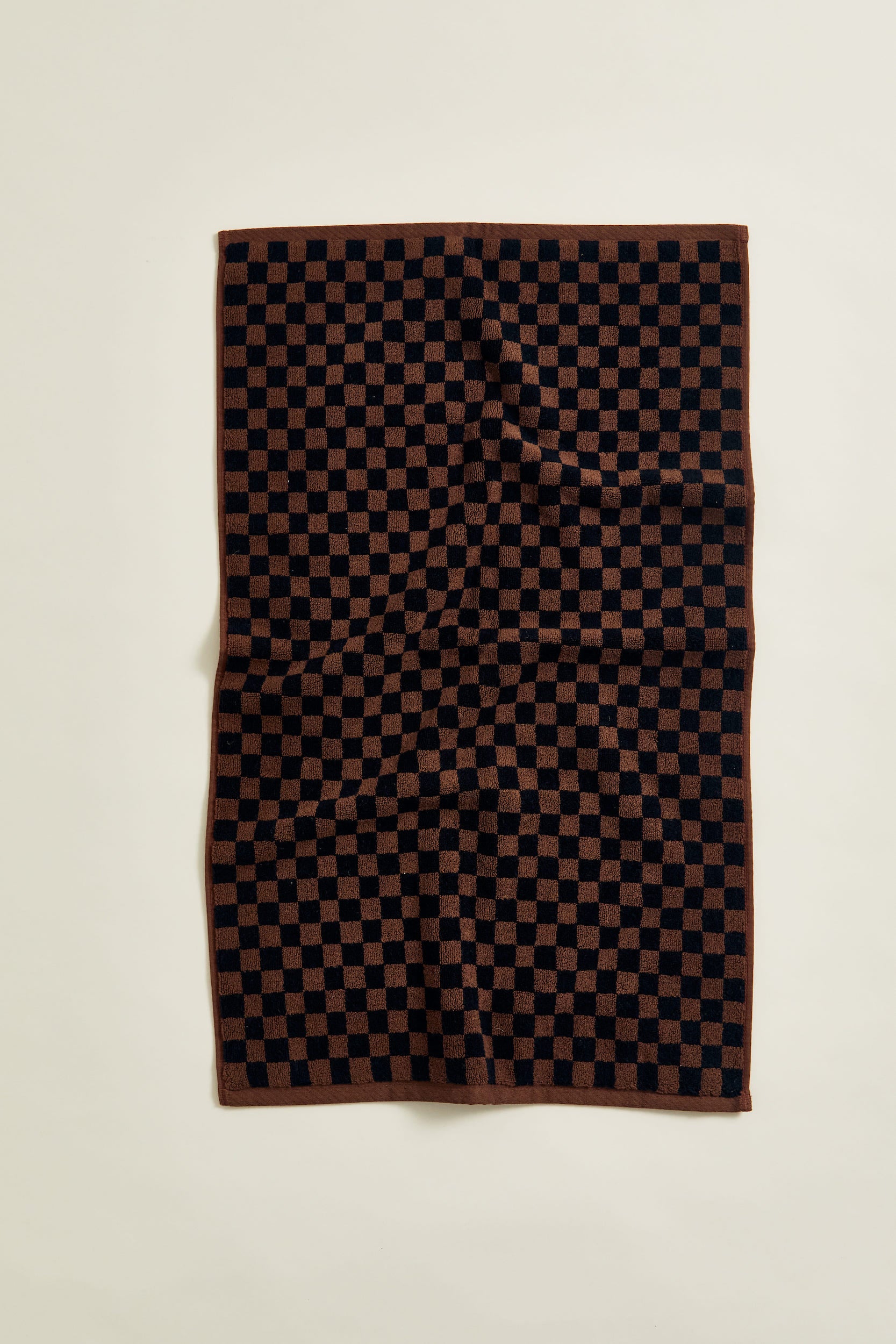 Beppu Organic Cotton Bath Mat in Tabac & Noir. An elevated, everyday bathroom essential with a heritage checkerboard print in brown and black that enriches the bathroom with a luxuriously soft, 100% organic cotton hand. 