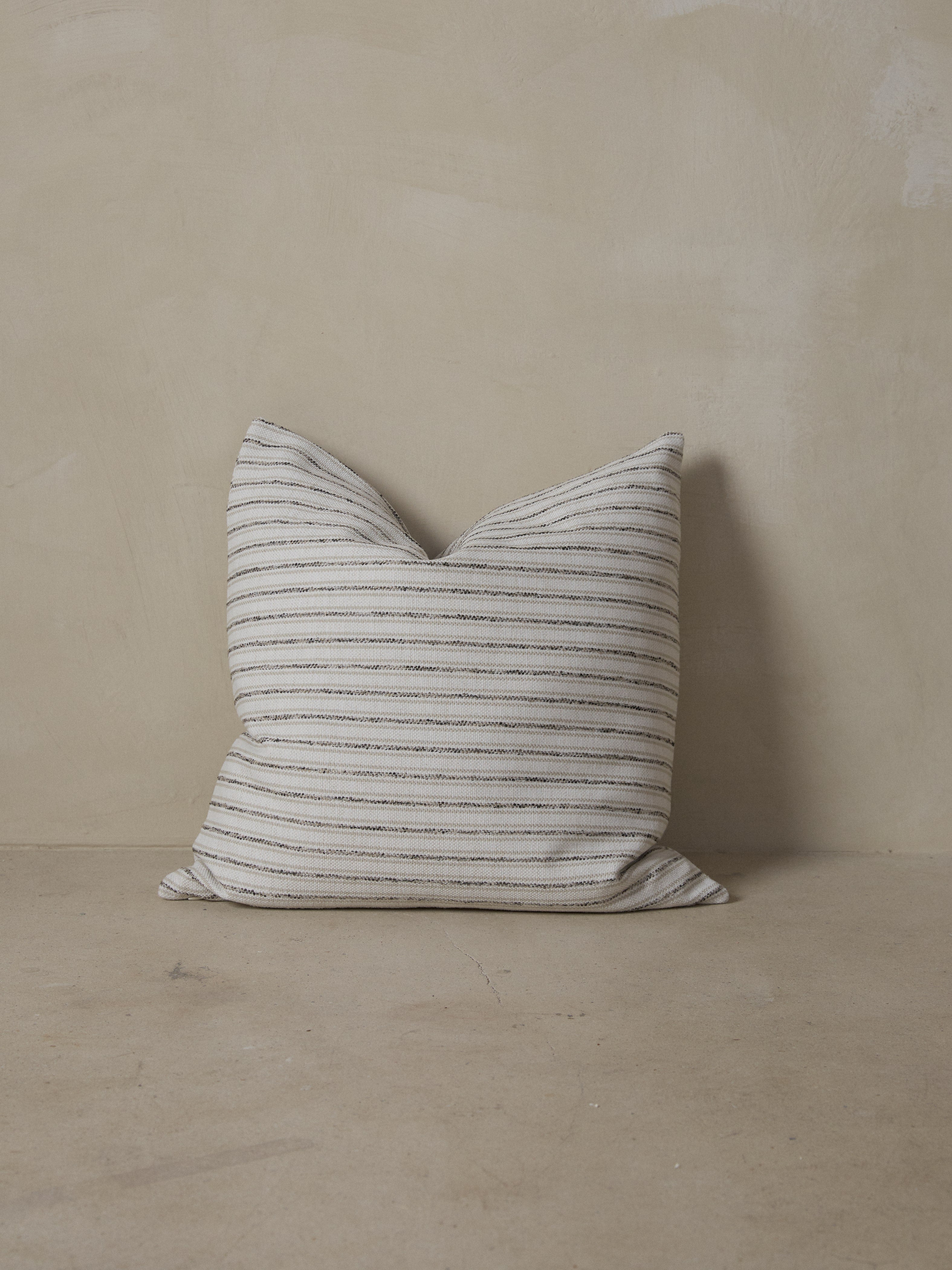 Striped double-sided decorative throw pillow in woven cream, black and natural stripes with off white backing. 