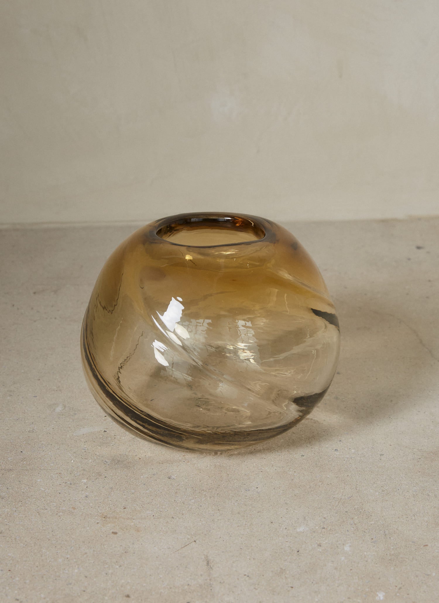 Round Water Swirl Vase. A mouth-blown vase in translucent light yellow glass recalling a whirl of cascading liquid, with twisting details that signify movement.
