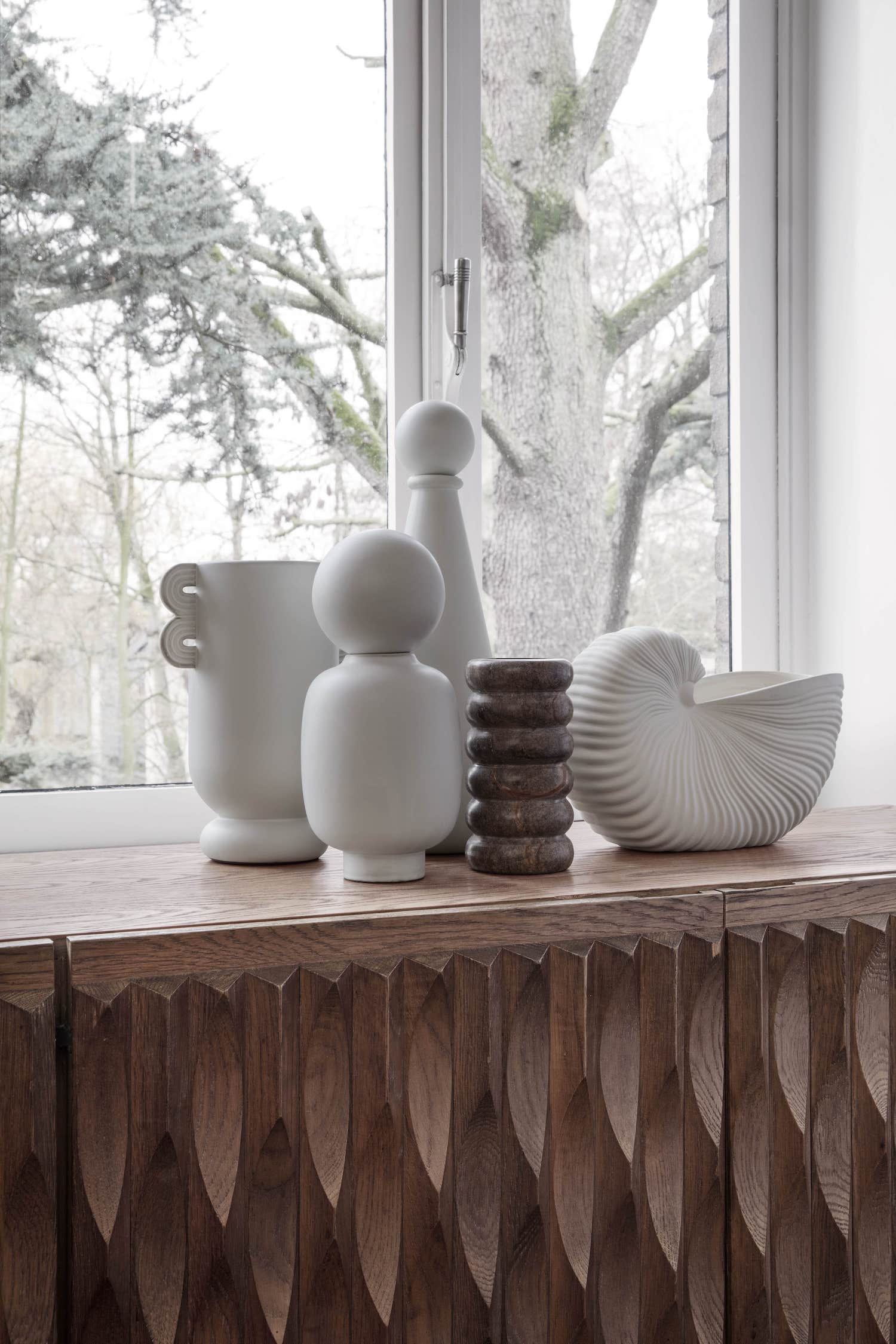 ferm LIVING Shell Pot on display with other decorative vessels on credenza.