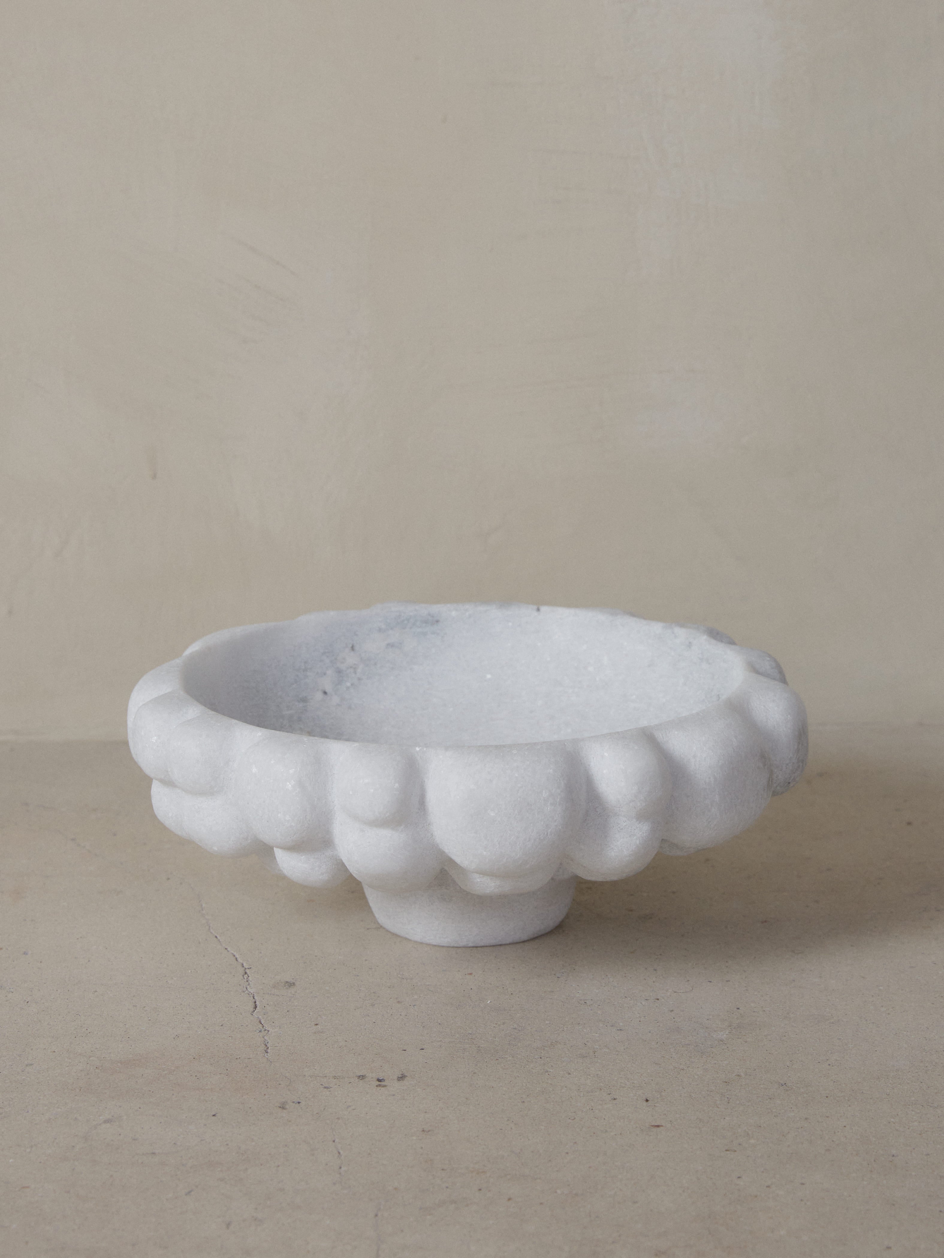 An exquisite statement piece. Crystalline Naxian marble hand sculpted into an oversized, tapered footed bowl with smooth interior and carved exterior, reminiscent of clouds. 
