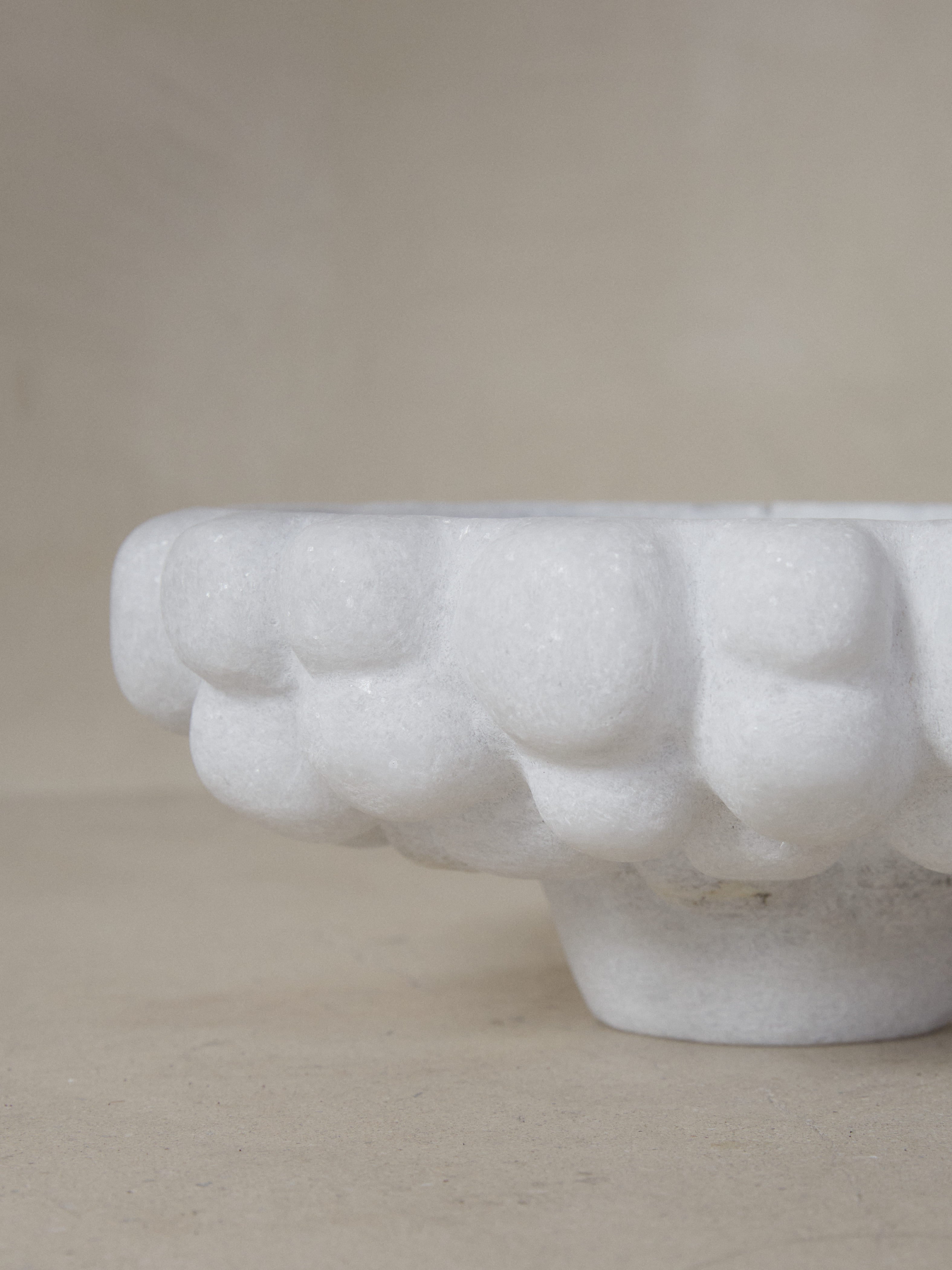 An exquisite statement piece. Crystalline Naxian marble hand sculpted into an oversized, tapered footed bowl with smooth interior and carved exterior, reminiscent of clouds. 