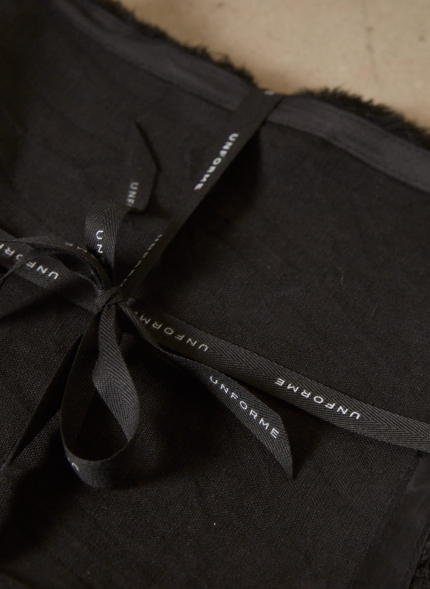Casually elegant, rich black linen napkin with a fringe edge and tonal silk bias trim. 