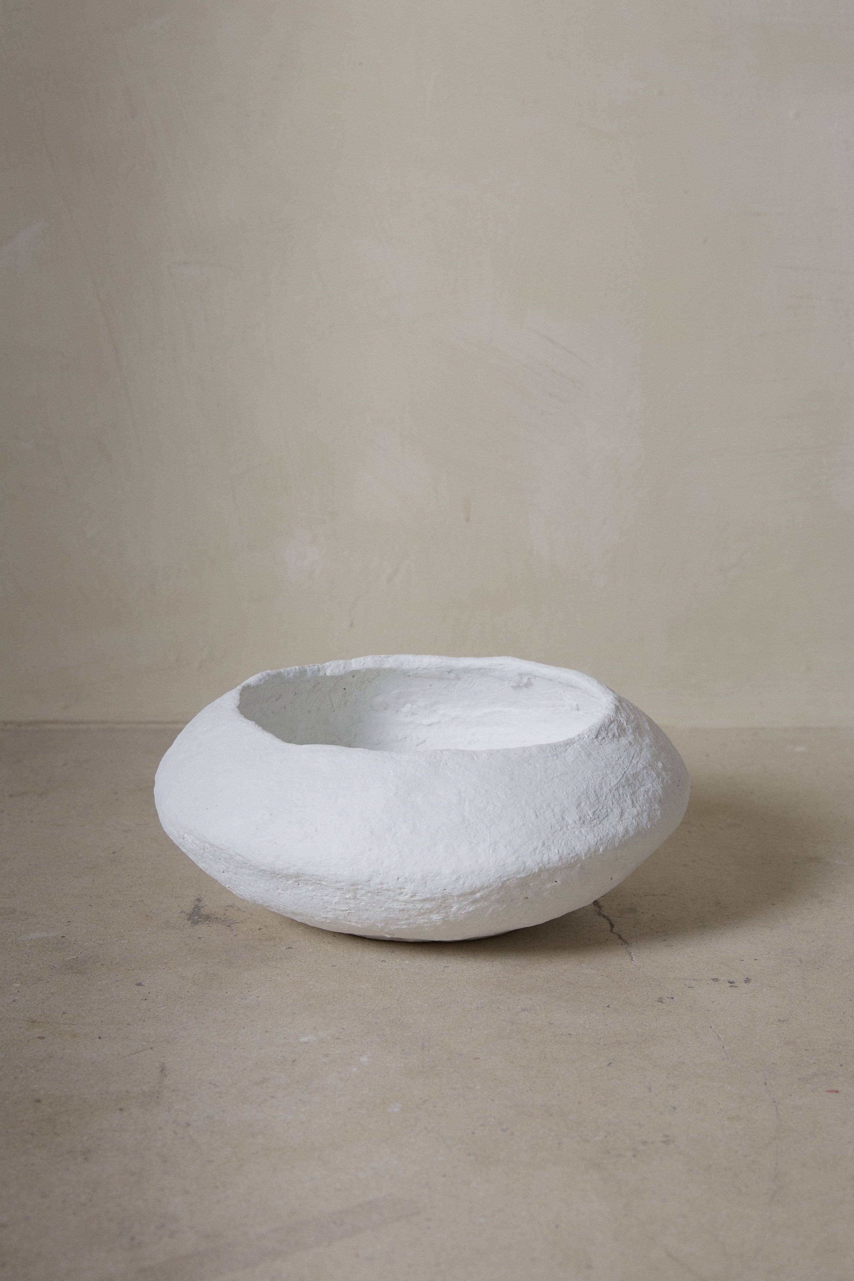 Hand sculpted, wide low bowl with irregular lip in natural white made from sustainable paper maché. 