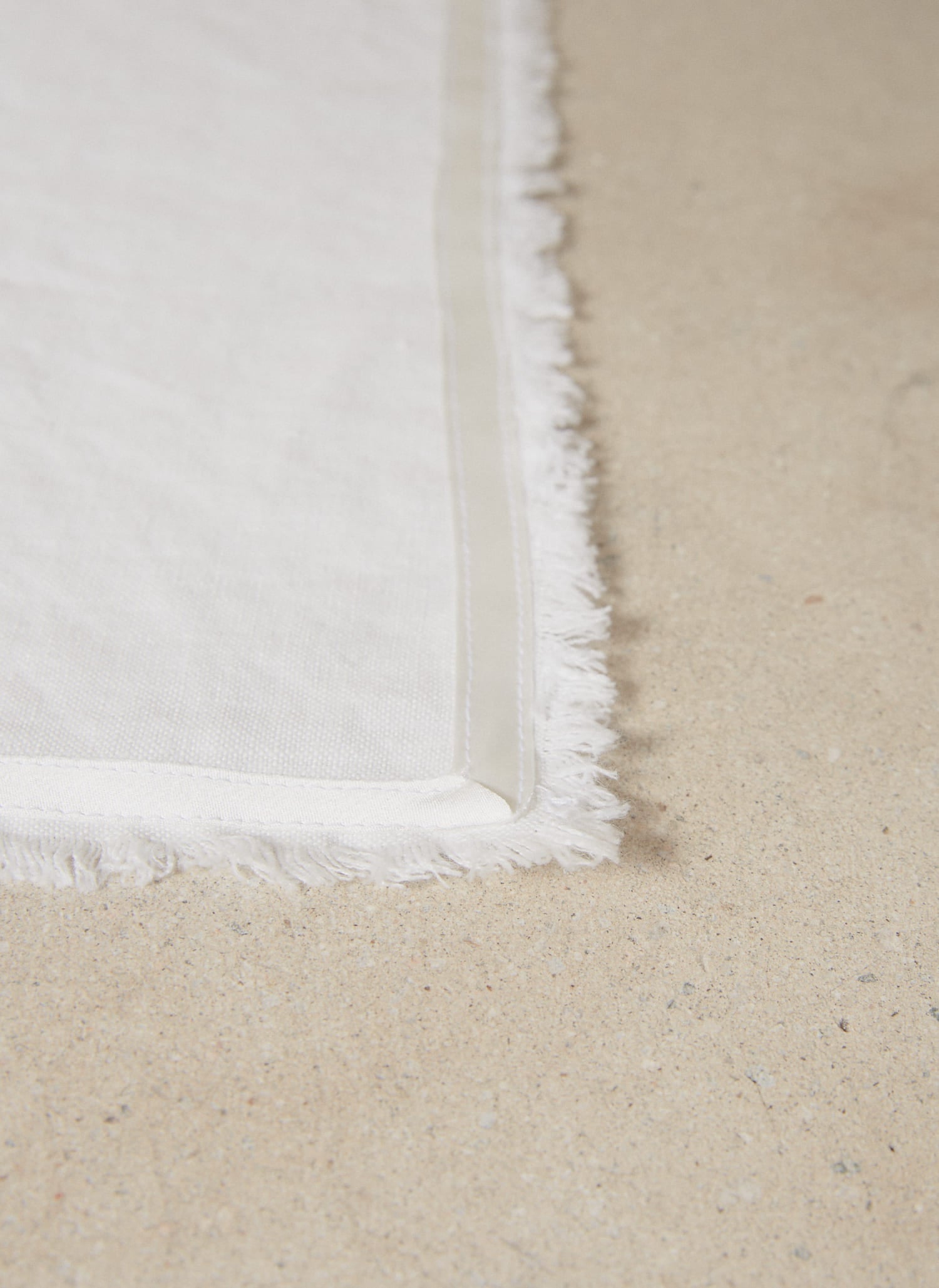 Casually elegant crisp white linen placemat with a fringe edge and tonal silk bias trim.
