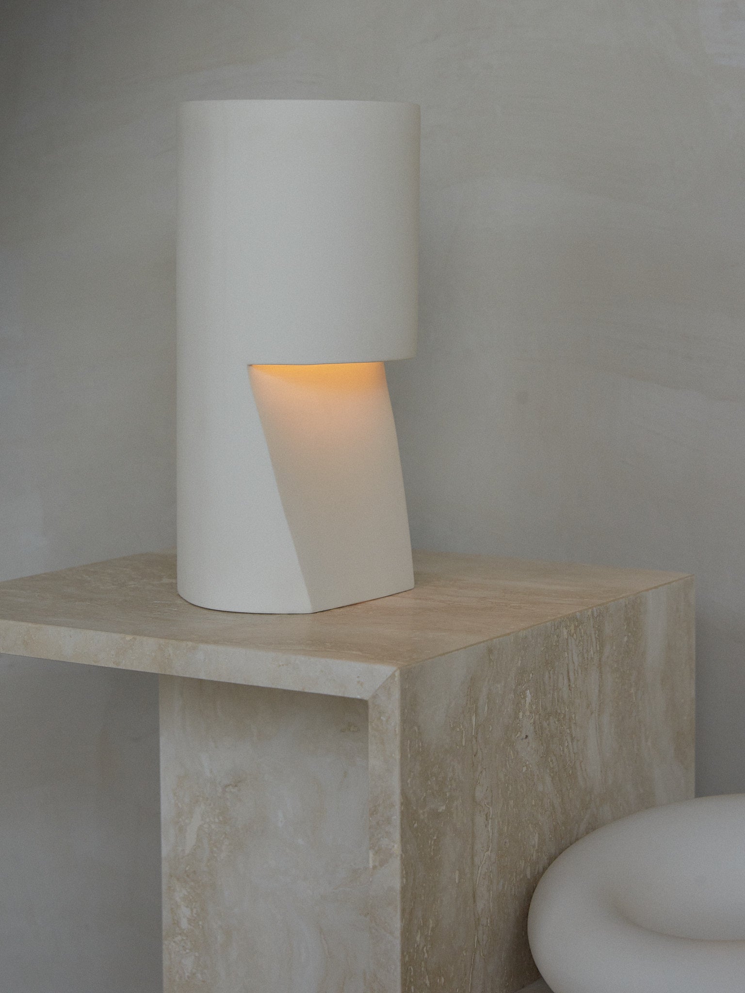 Pillar Light. A cylindrical, hand sanded porcelain pillar table lamp in natural white.  Light shines subtly from a hollow outcropping in the porcelain body. 