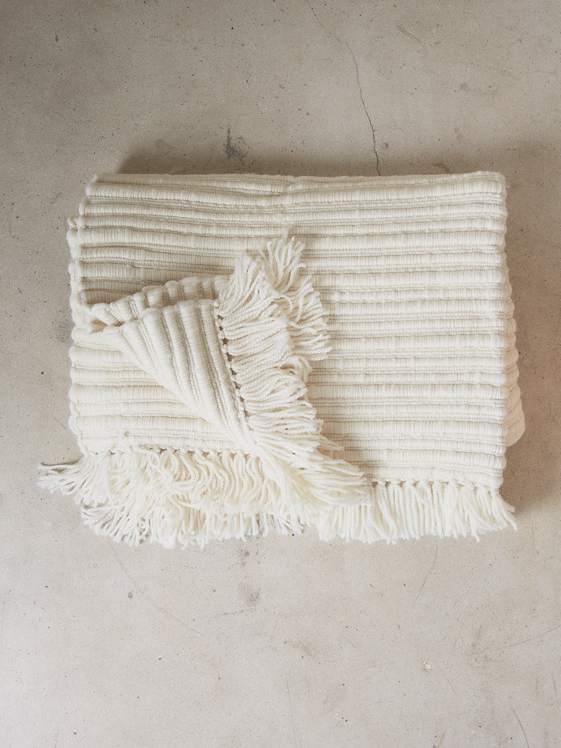 Aspen Blanket. A substantial, tactile and weighty statement throw blanket hand spun from the softest merino wool in an elegant, neutral cream color.