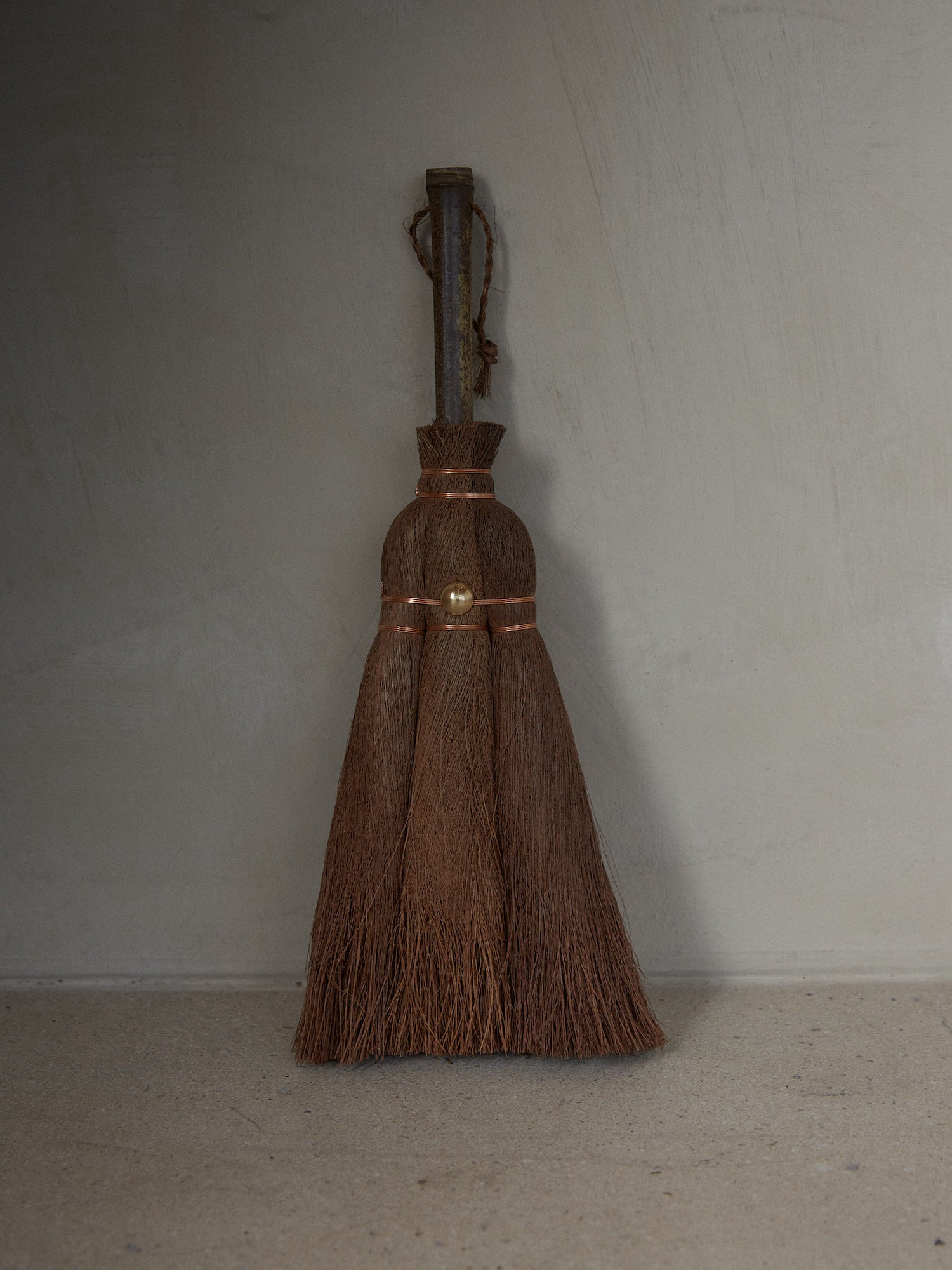 Angled Vintage Hand Broom. Rare find. Natural hand held broom with a short bamboo handle hand crafted of fine Indian Palm fibers and joined by copper wire for a light, clean sweep.