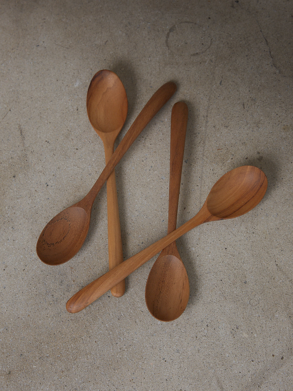 Elegant, elongated mixing spoon with arched handle, hand carved from natural teak wood.