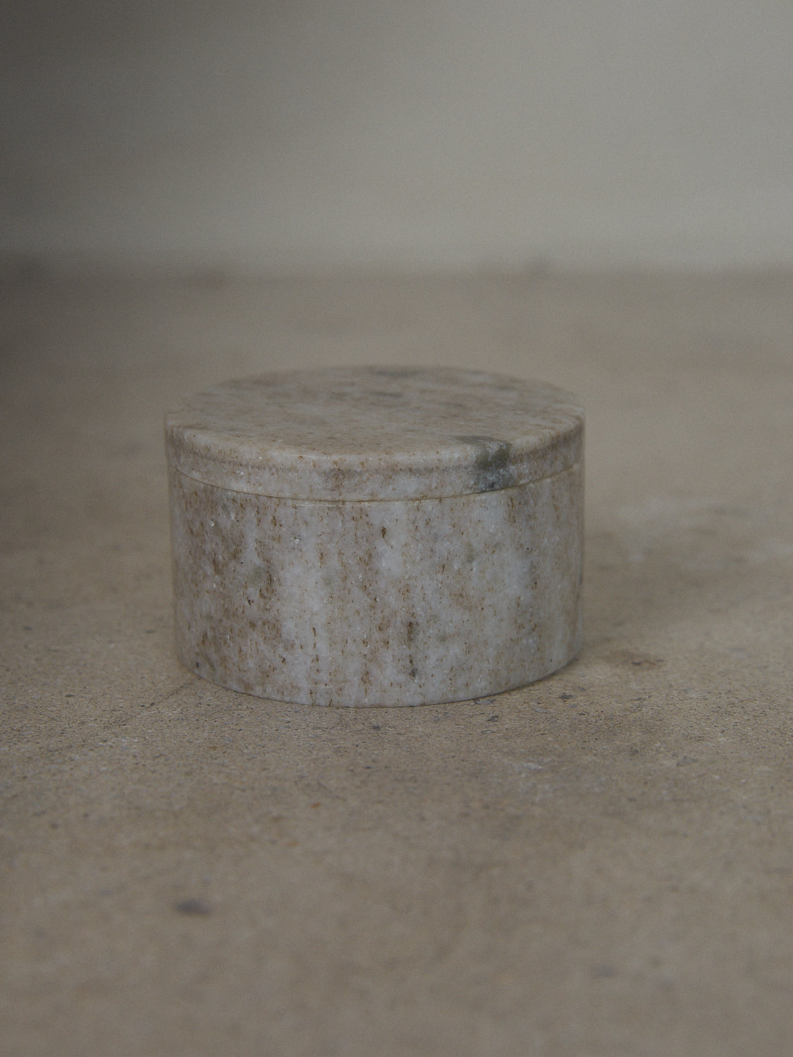 Low, round lidded box carved from natural grey marble.