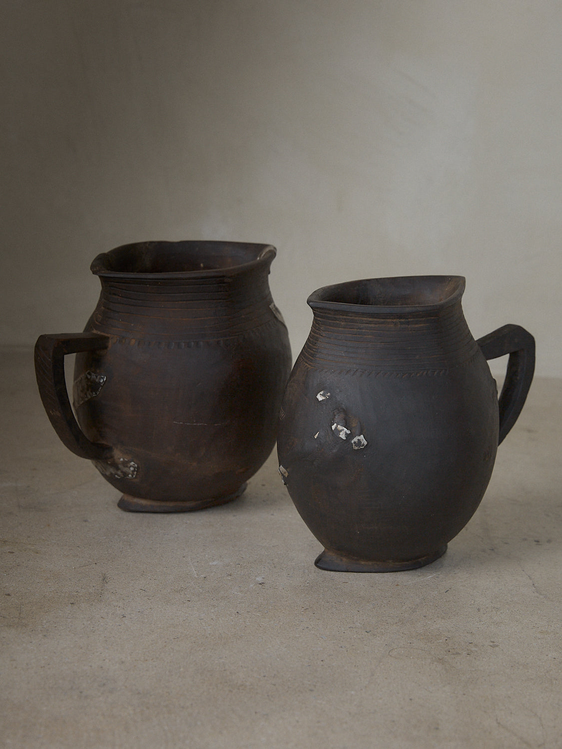 Small, hand carved milk pitcher with artful etching and hand-forged metal repair details in dark natural wood. 