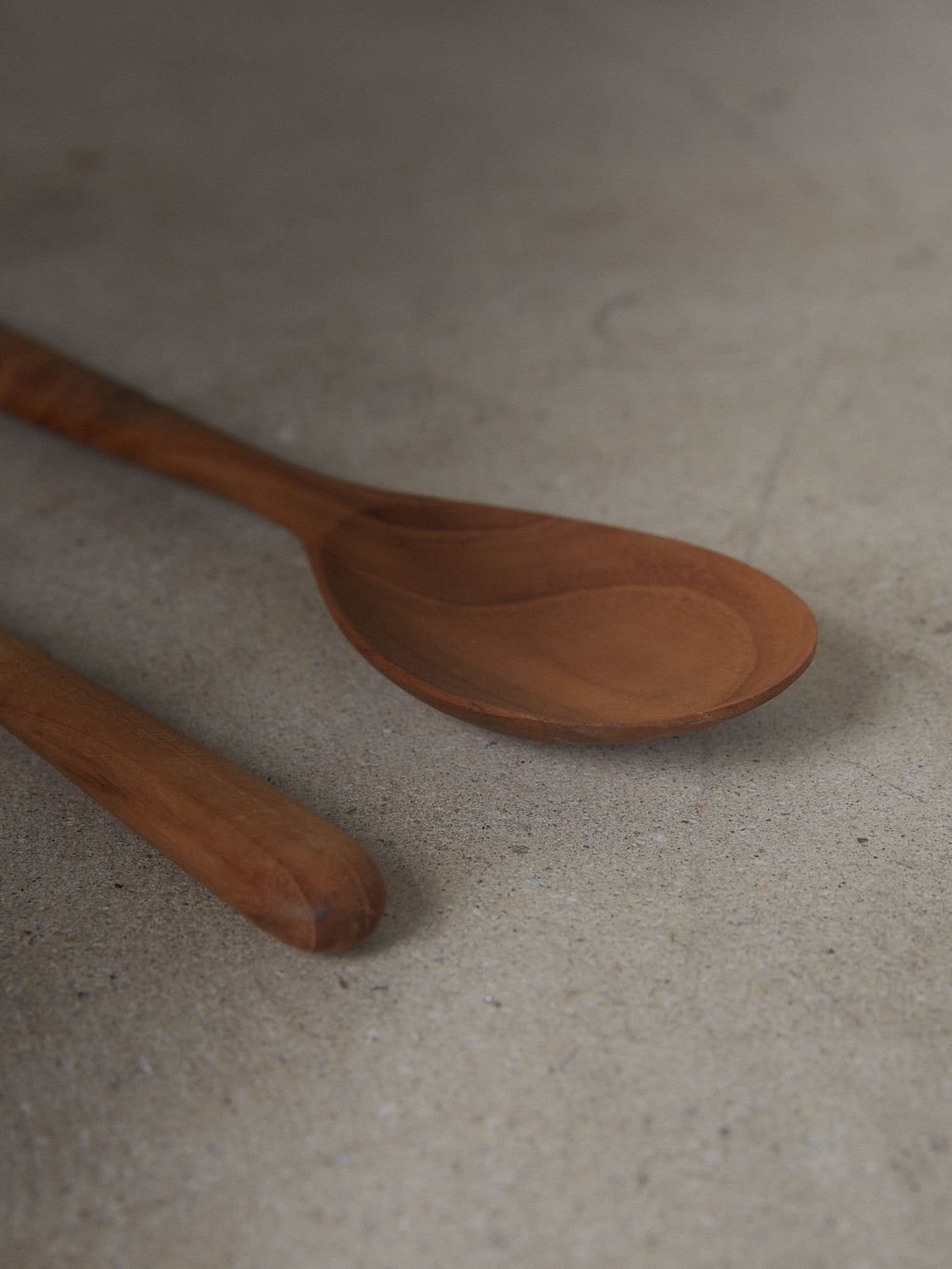 Pair of minimalist utensils for serving salad in natural teak wood.
