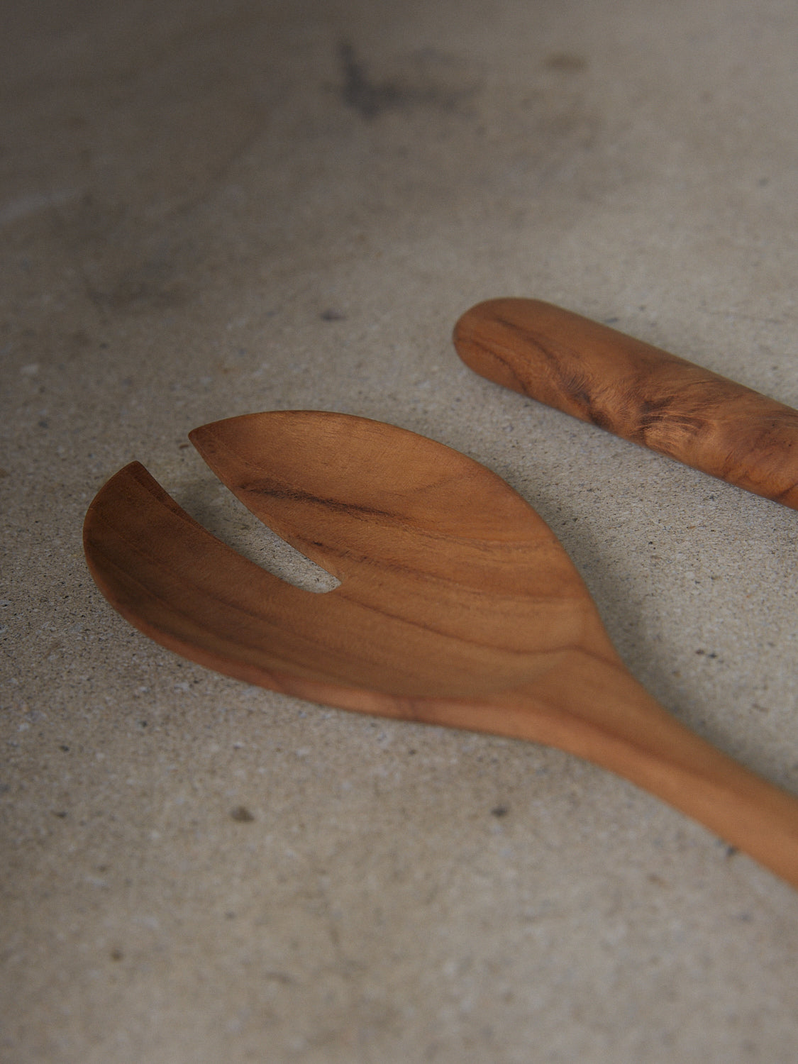 Pair of minimalist utensils for serving salad in natural teak wood.