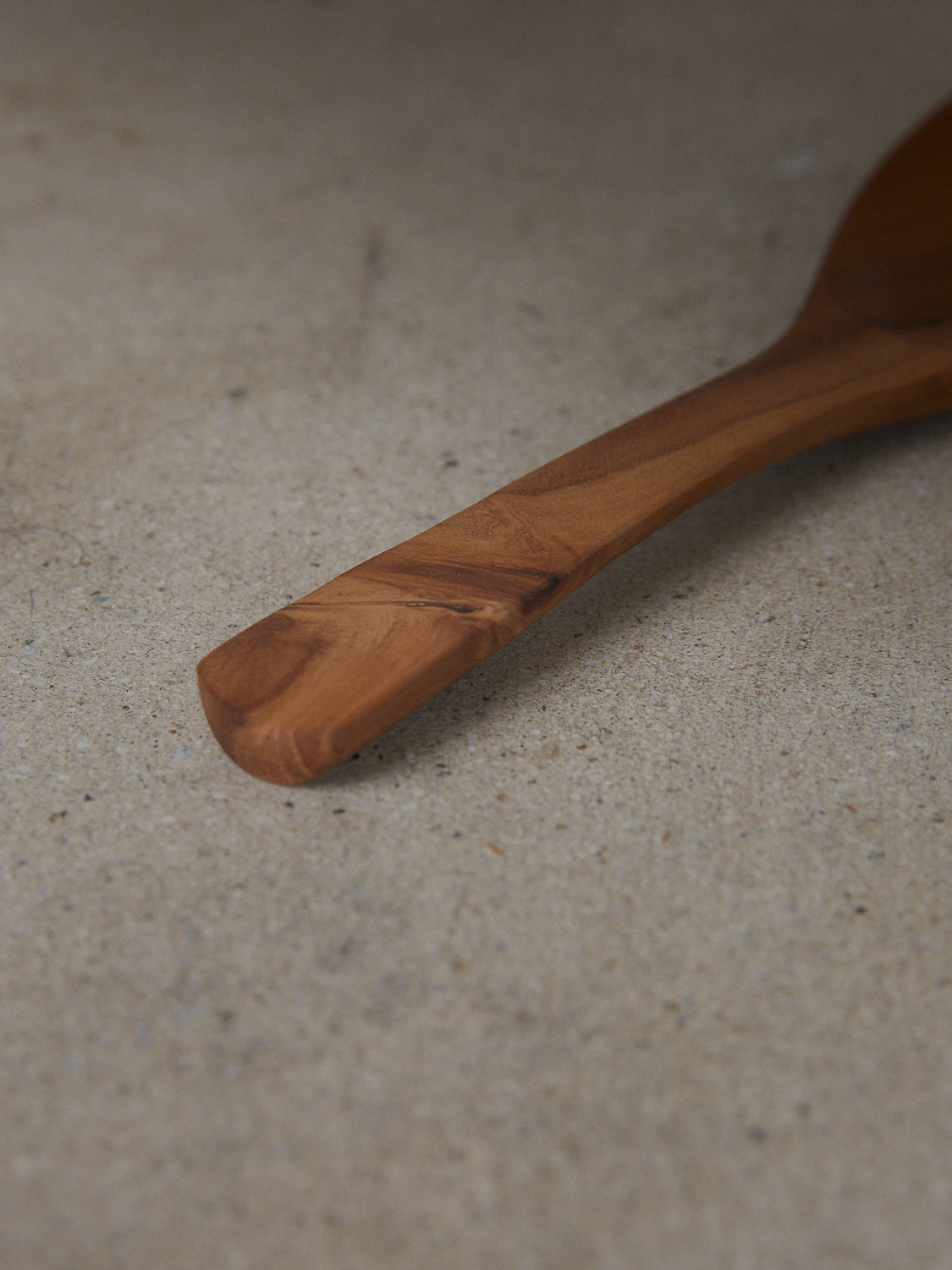  Elegantly curved scoop spoon with gently arched handle, hand carved from natural teak wood.