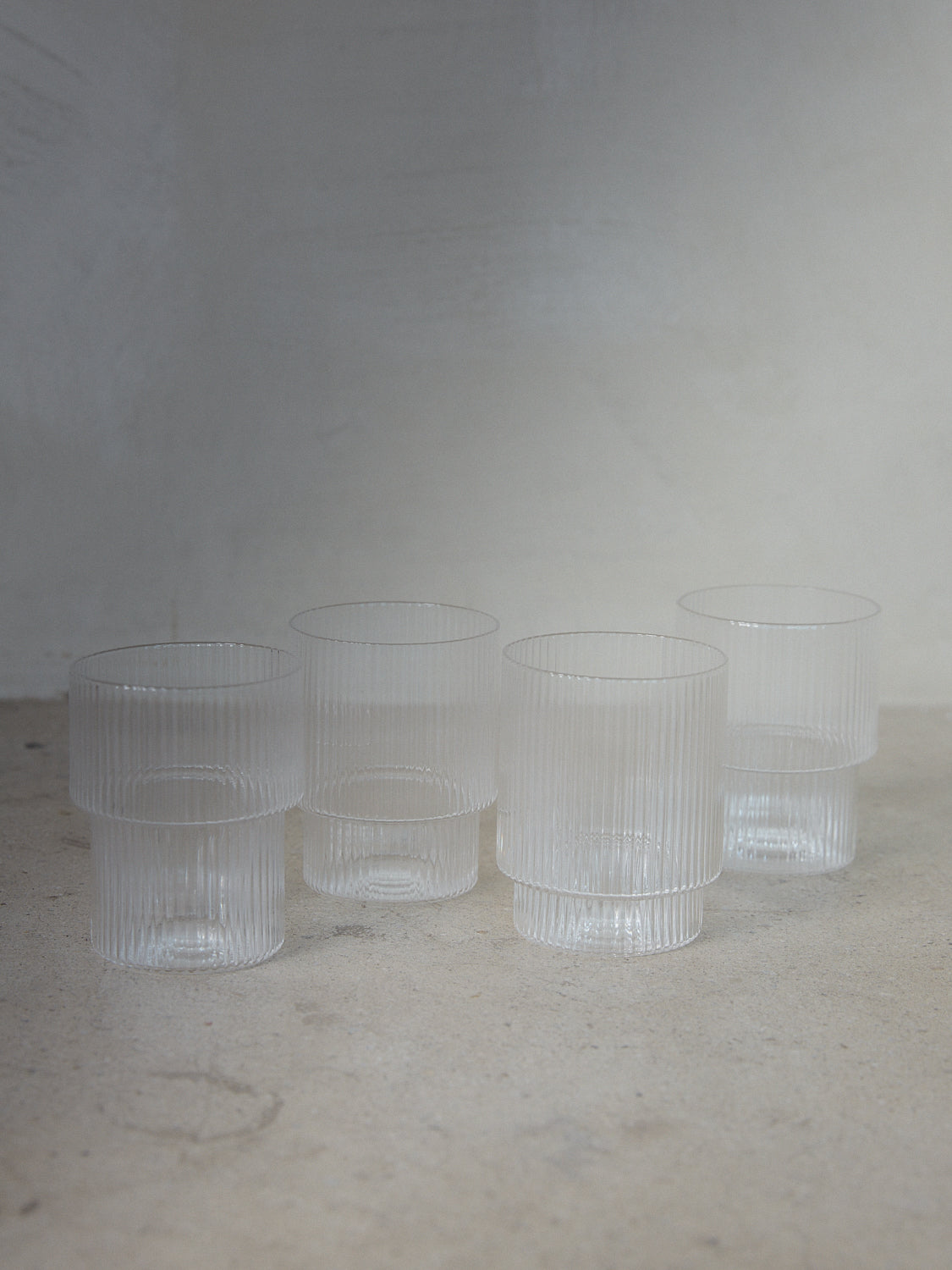Ripple Glasses Set/4. A set of four unique drinking glasses with varied geometric forms and a sophisticated vertical ripple surface in clear transparent glass.