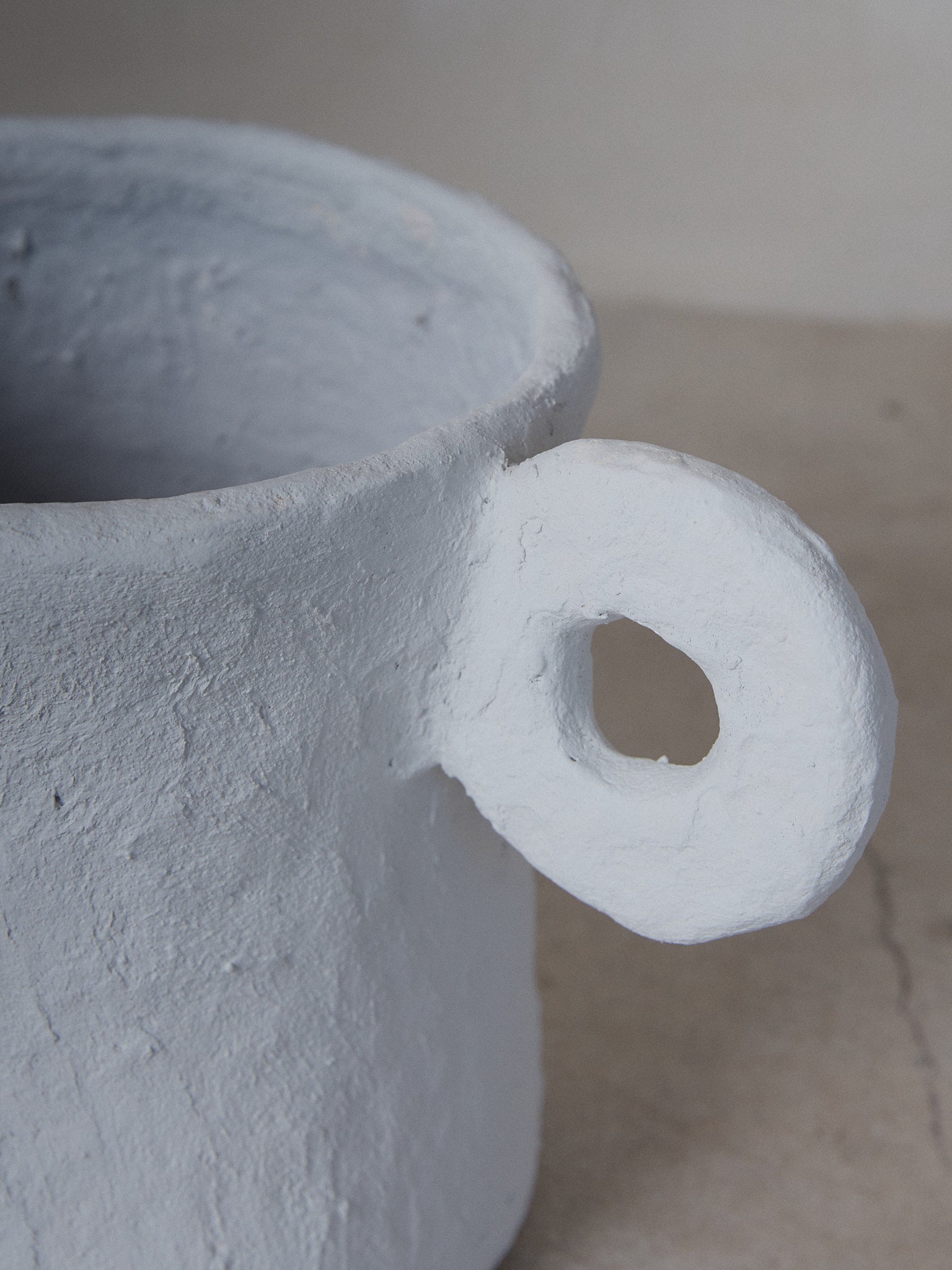 Medium Earth Pot. A sculptural, beige planter pot with looped handles, a linear structure and otherworldly vibe.