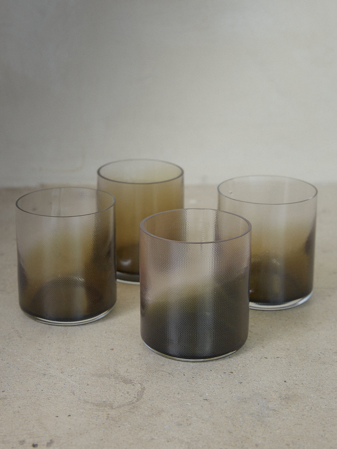 Smoke Green Raw Glass Set. Set of four tumbler glasses mouth blown into raw woven molds, textured and shaped by soft textile copper and accented with a smoke green gradient color. 