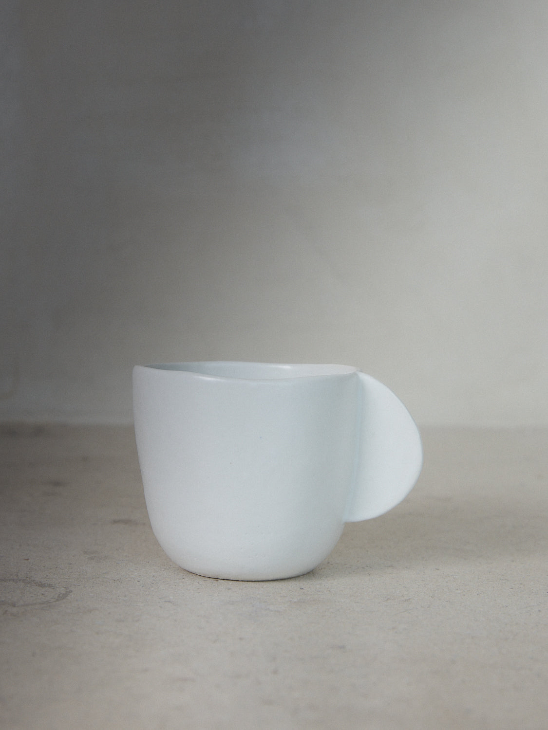 Raw Coffee Cup. Exclusively ours. Hand sculpted coffee cup with a solid, semicircle handle in matte, milky white stoneware.