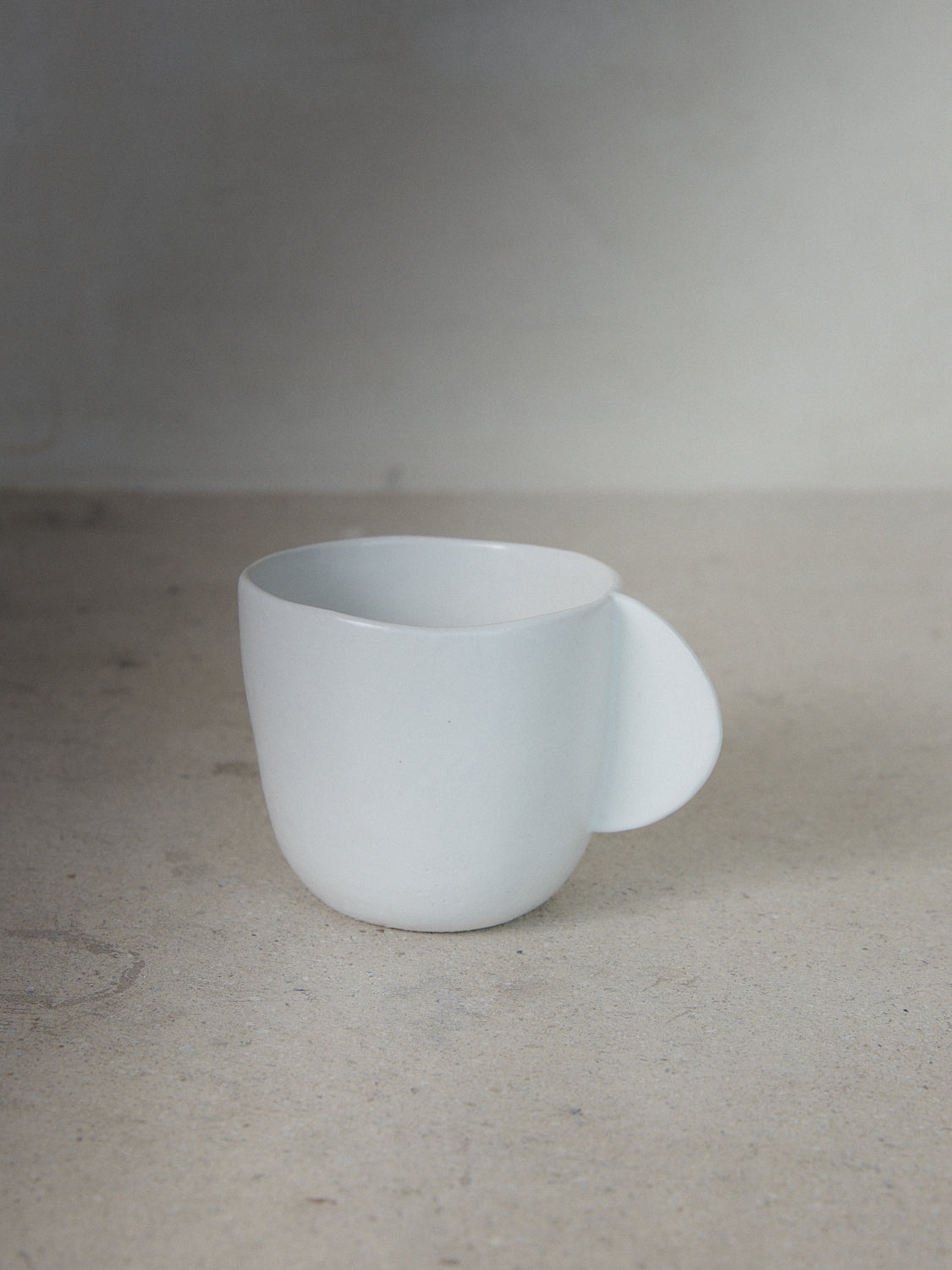 Raw Coffee Cup. Exclusively ours. Hand sculpted coffee cup with a solid, semicircle handle in matte, milky white stoneware.