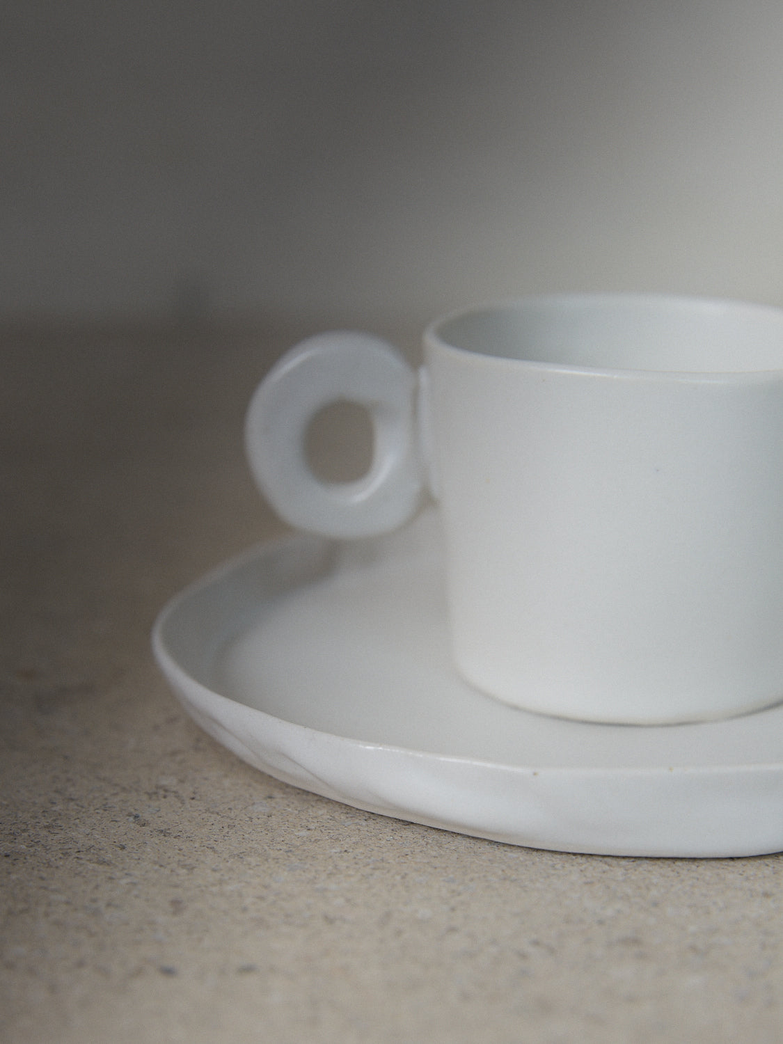 Raw Espresso Cup Set. Exclusively ours. A set of two playful, handmade espresso cups with round handles and matching saucers in matte white stoneware. 