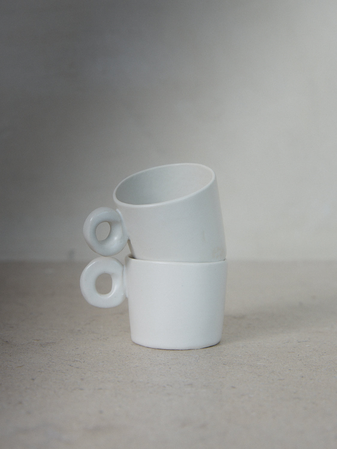 Raw Espresso Cup Set. Exclusively ours. A set of two playful, handmade espresso cups with round handles and matching saucers in matte white stoneware. 