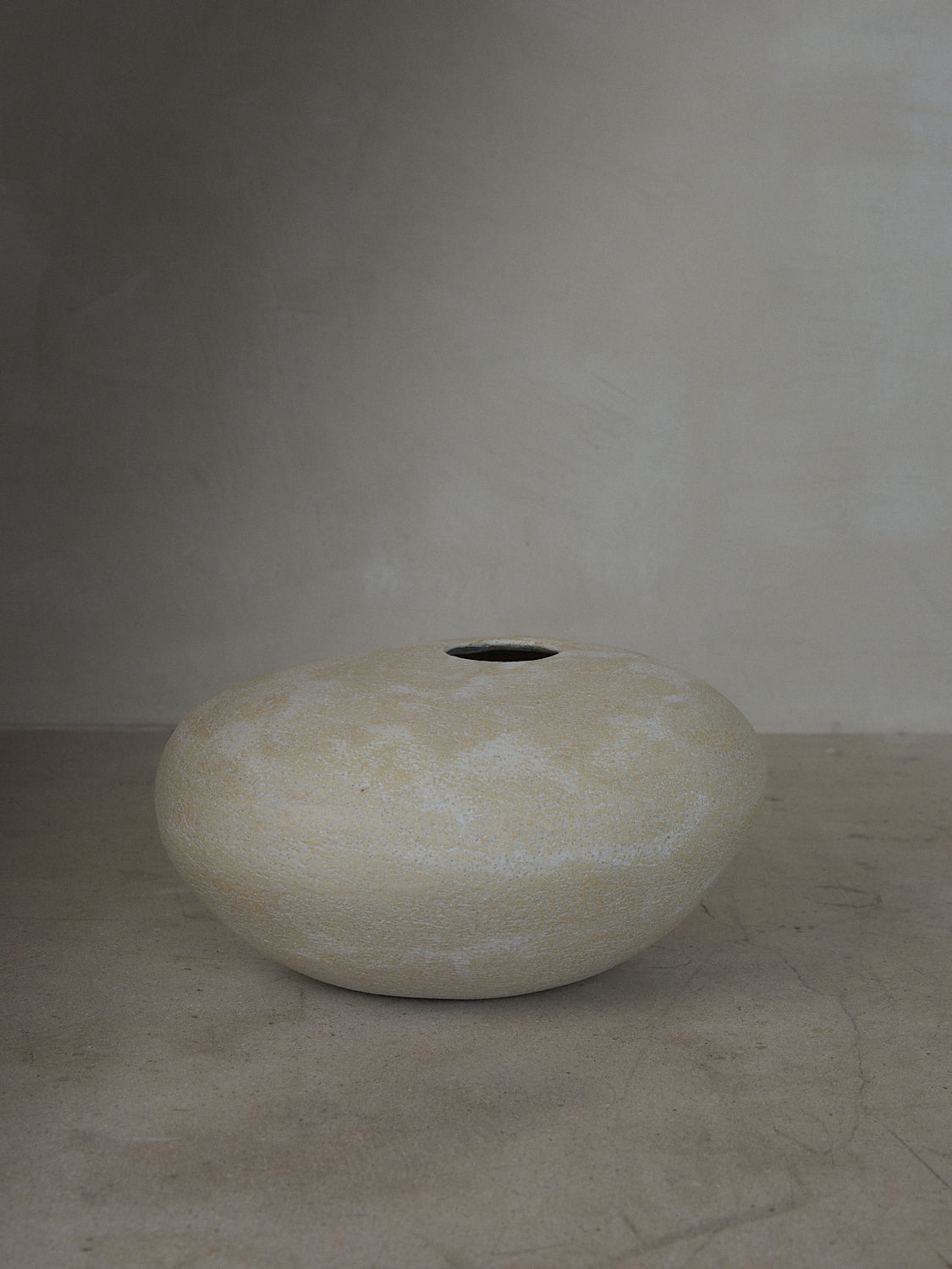 A statement vase inspired by aged river rocks with an irregular oblong shape in a matte stone finish.
